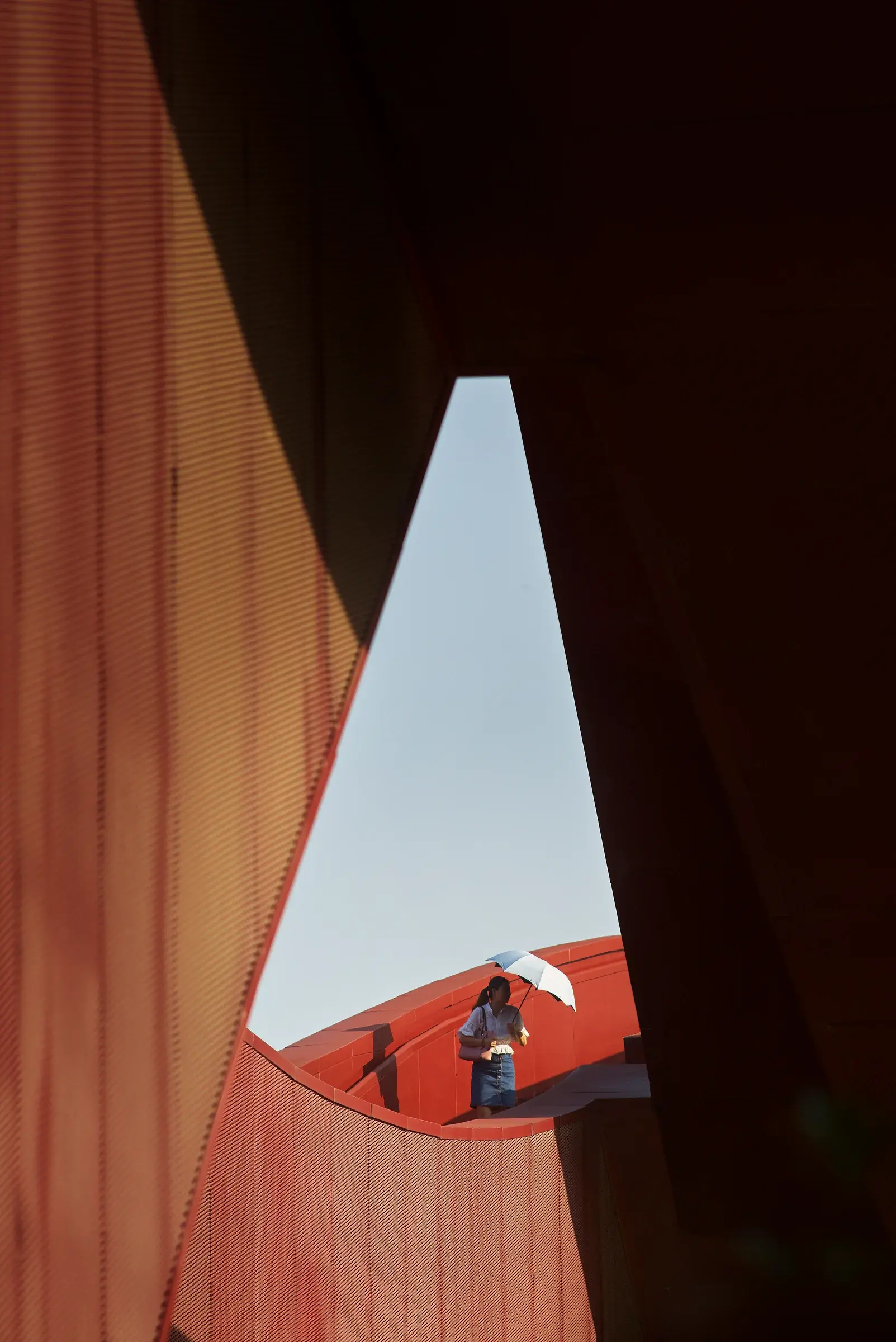 Lucky Knot Bridge by NEXT Architects in Changsha, China, seen in a wide view with its looping red structure over the river, Photography Julien Lanoo