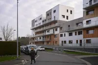 Van Pelt Housing by TANK Architectes in Lens, France, with terraces beside the wooded park and landscaped embankment.